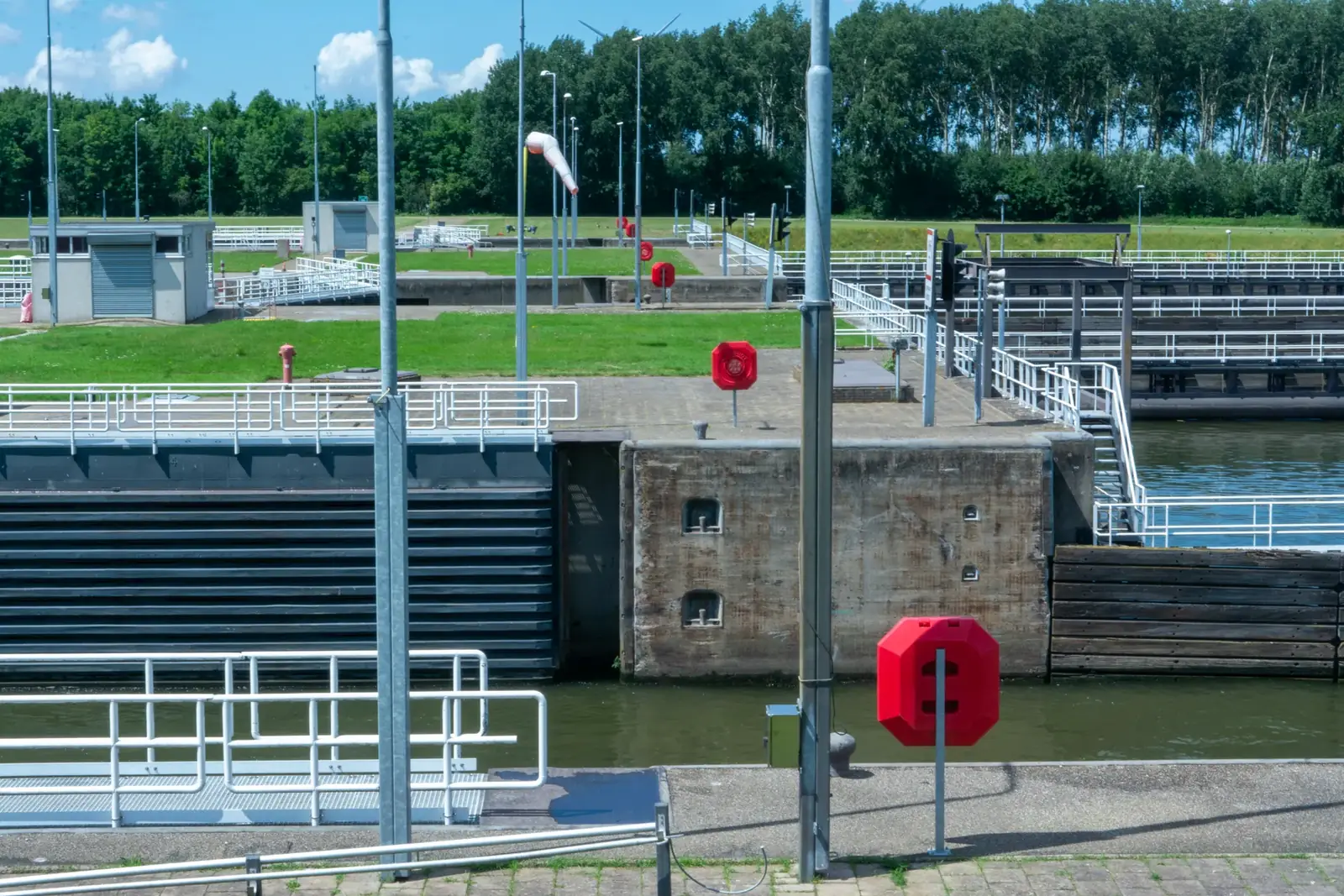 A modern canal lock system featuring safety buoys and lock gates on a sunny day.