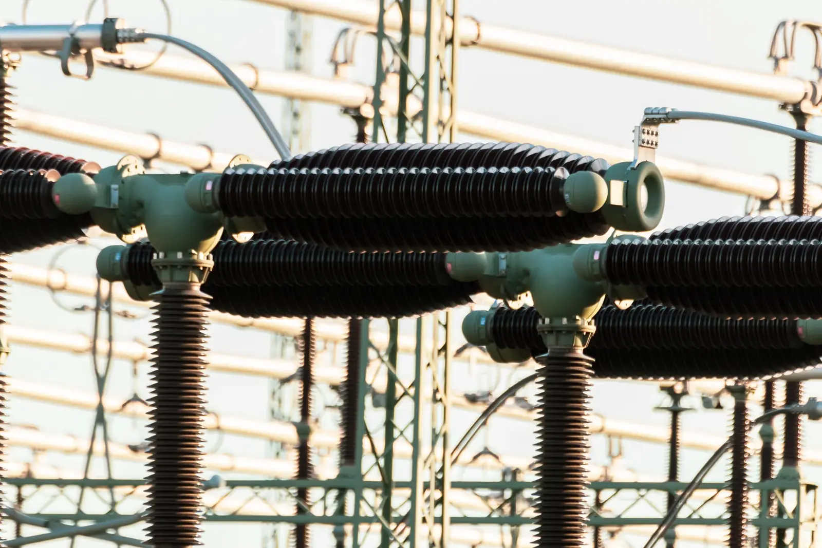 Close-up of outdoor electrical power equipment with insulators and conductors.