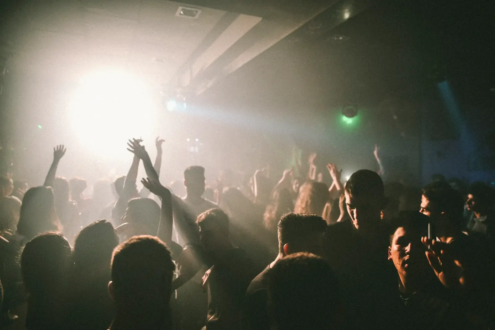 A lively nightclub with people dancing and enjoying music under colorful lights.