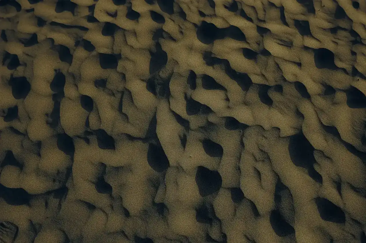 Aerial view of intricate sand patterns on a beach at sunset, capturing nature's artwork.