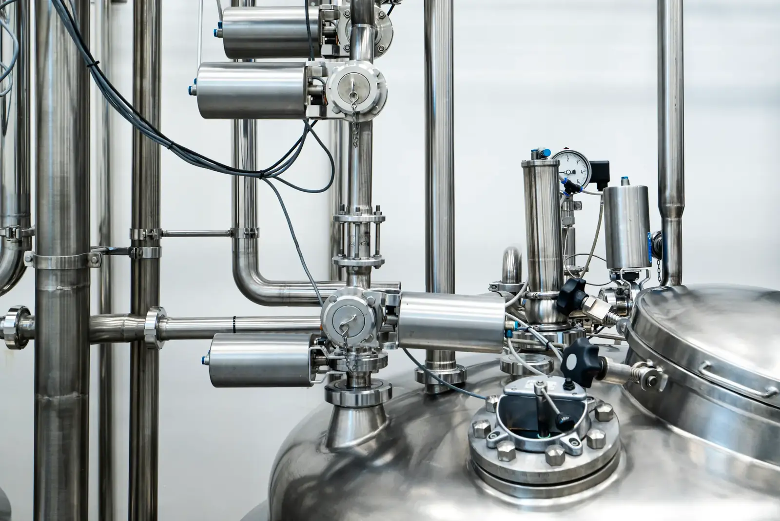 Close-up of stainless steel machinery and pipes in an industrial setting, showcasing modern engineering.