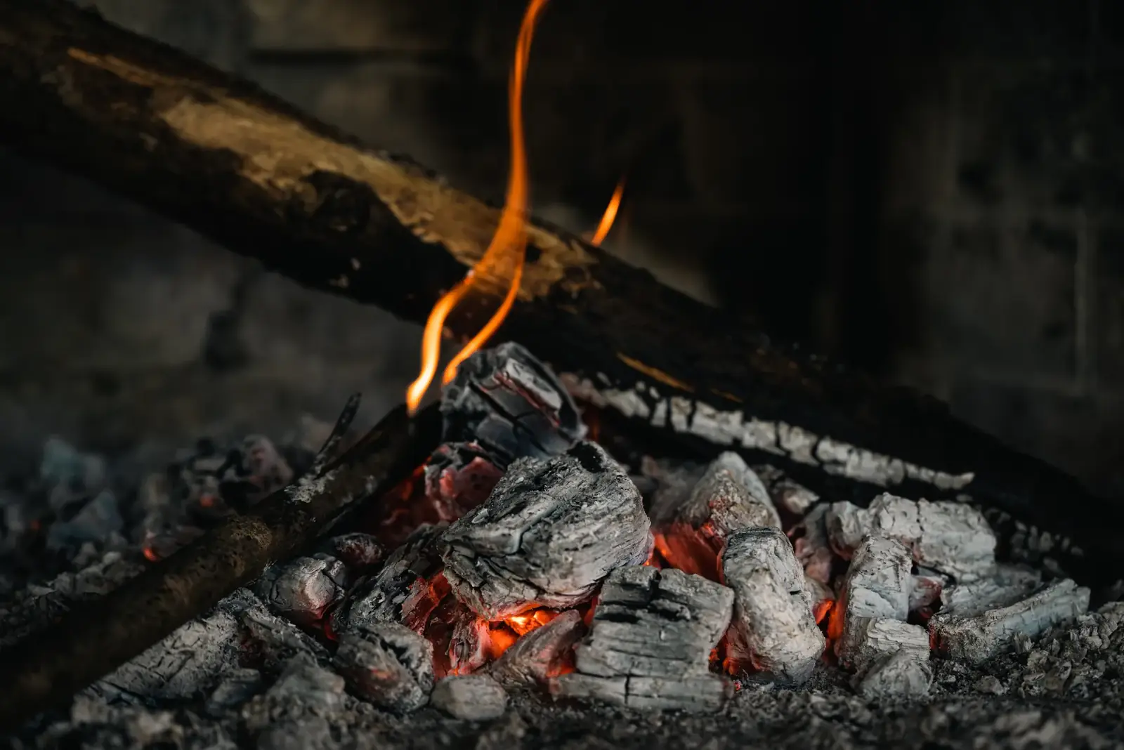 A detailed view of hot embers and burning firewood, creating a warm atmosphere.