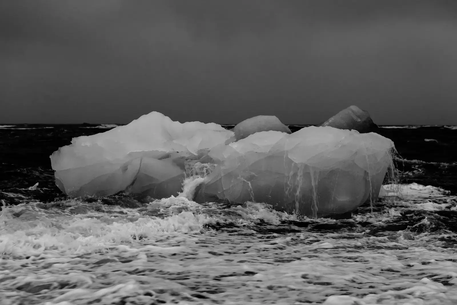 Black and white photo of an iceberg in a stormy ocean, symbolizing climate change.