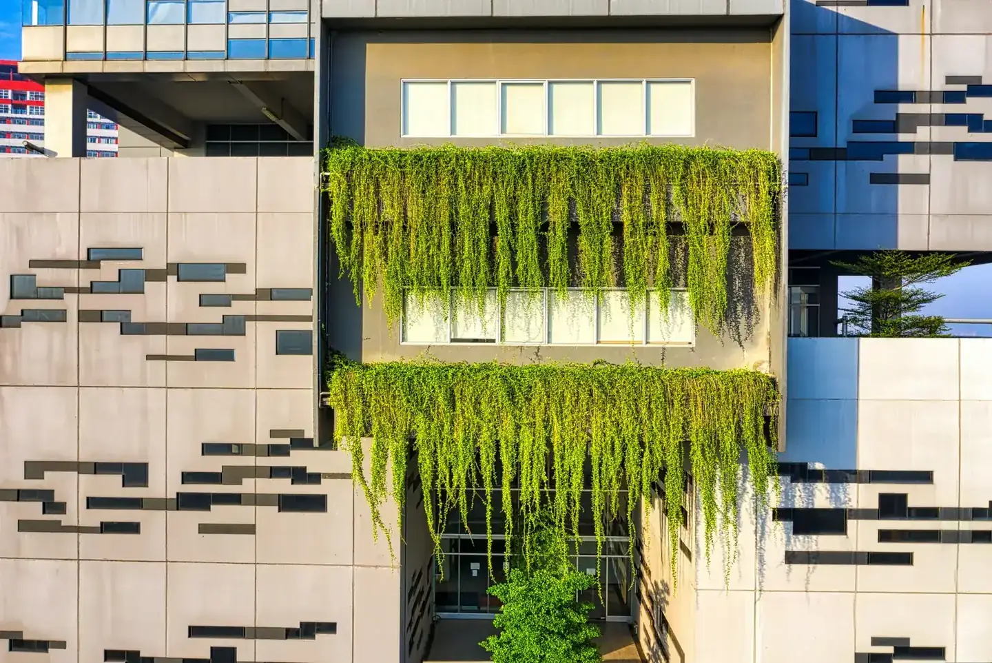 Contemporary building facade with lush green plants in urban Banten, Indonesia.