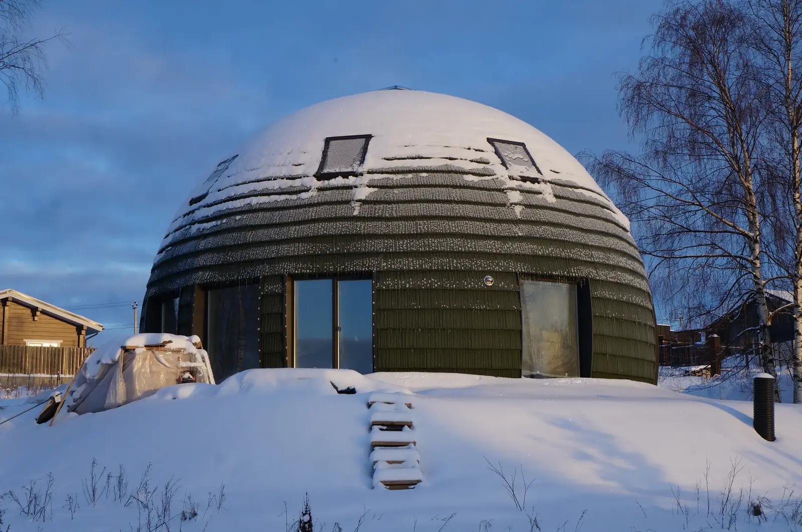 A unique dome-shaped house covered in snow during winter, creating a serene landscape.